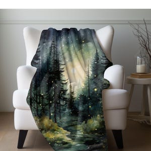 May include: A soft, plush throw blanket featuring a watercolor painting of a forest scene at night. The painting depicts a stream running through a dark forest with tall trees and glowing fireflies. The background is a soft, light blue with a hint of green.