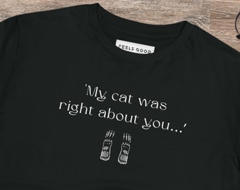 May include: Black t-shirt with white text that reads 'My cat was right about you...' and two paw prints below the text.