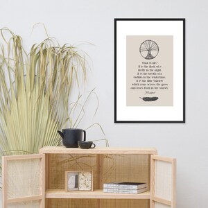 Może przedstawiać: Oprawiony wydruk z czarną obw&oacute;dką zawiera cytat o życiu. Tekst jest czarny, z ilustracją drzewa na g&oacute;rze i pi&oacute;rem na dole. Tło jest jasnobeżowe.