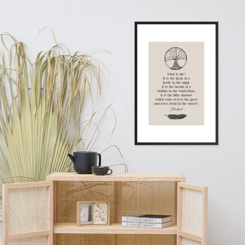 Może przedstawiać: Oprawiony wydruk z czarną obw&oacute;dką zawiera cytat o życiu. Tekst jest czarny, z ilustracją drzewa na g&oacute;rze i pi&oacute;rem na dole. Tło jest jasnobeżowe.