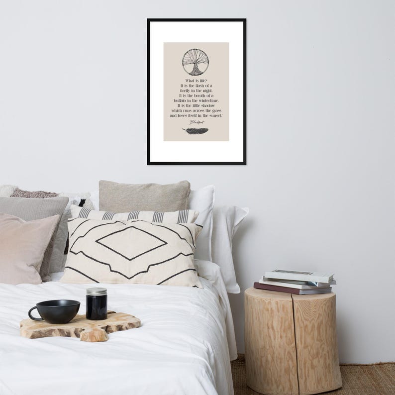Może przedstawiać: Oprawiony wydruk z czarną obw&oacute;dką, z beżowym tłem z ilustracją drzewa i tekstem. Tekst brzmi "Co to jest życie?" po kt&oacute;rym następuje wiersz i ilustracja pi&oacute;ra. Wydruk jest wyświetlany nad ł&oacute;żkiem z dekoracyjnymi poduszkami.