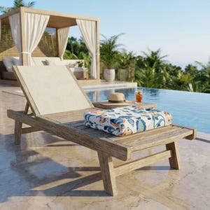 A wooden lounge chair with a colorful towel and a glass of orange juice sits on a tiled patio overlooking a pool, with a wooden pavilion and palm trees in the background.