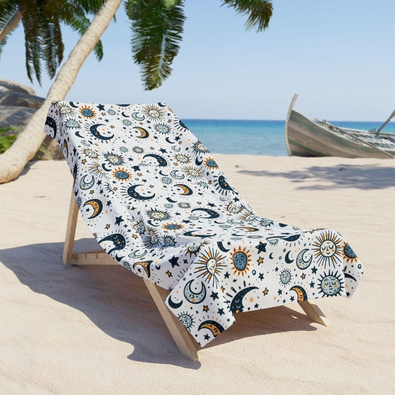 A beach chair with a patterned towel draped over it, situated on a sandy beach with palm trees and a boat visible in the background.
