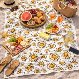 A picnic spread on a beach blanket, featuring a variety of food and drinks, including a basket of fresh fruit, bread, cheese, and crackers.