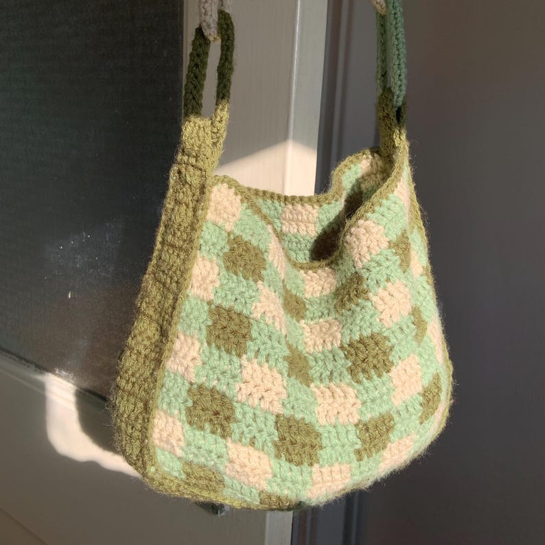 May include: A green and white checkered crocheted tote bag with a thick strap.