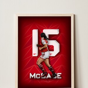 Könnte beinhalten: Ein gerahmtes Poster mit rotem Hintergrund und einer weißen Nummer 15. Eine Frau in einem rot-weißen Fußballtrikot läuft vor der Nummer. Der Text "McCabe" befindet sich unter der Nummer.