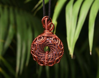 May include: A circular purple gemstone pendant encased in intricate copper wire wrapping. The pendant features a central hole and is suspended from a black cord. The wire design consists of swirling patterns and tight coils.