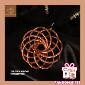Może przedstawiać: Miedziany naszyjnik z wisiorkiem o plecionym, okrągłym wzorze. Wisiorek zawieszony jest na czarnym sznurku ze srebrnymi akcentami. Tło stanowi ciemna, teksturowana tkanina. Widoczny jest napis "The Only Shop of Tensorstore".