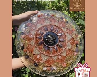 May include: A clear, circular resin art piece with a mandala design. The piece features a central black stone surrounded by amethyst and other colorful stones, copper wire, and gold glitter. The text "THE ONLY SHOP OF TENSORSTORE" is visible.