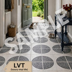 Op de afbeelding: Gangvloer met luxe vinyltegels (LVT) met een herhalend patroon van zwarte en witte concentrische halve cirkels. De tegels zijn 1,5 mm dik. De gang heeft een groene deur, een donkerblauwe tafel en een rieten mand.