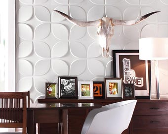 May include: A decorative wall arrangement featuring a white cow skull with long horns, mounted above a dark wood dresser. Several framed photos and a lamp are arranged on the dresser. The wall has a white, patterned design.