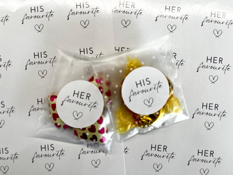 May include: Two clear plastic bags filled with small wrapped sweets. One bag has a white circle sticker that says "HIS favourite" with a heart. The other bag has a white circle sticker that says "HER favourite" with a heart. There are several white circle stickers with the same text on a white background.