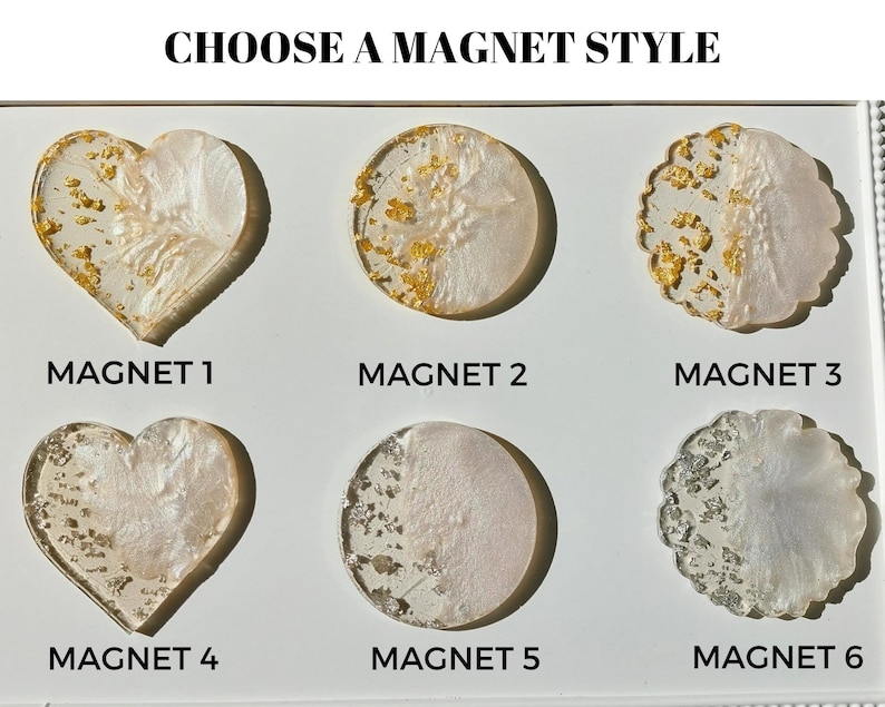 Pu&ograve; includere: Una selezione di sei calamite decorative di varie forme, tra cui cuori e cerchi. Ogni calamita presenta una base bianca perlescente con accenti di foglie d'oro o d'argento. Il testo "CHOOSE A MAGNET STYLE" &egrave; in alto.