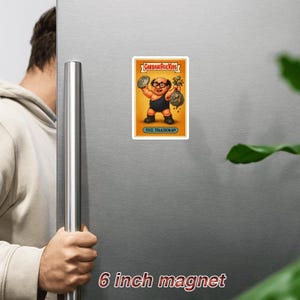 Puede incluir: Un imán de 15 cm con una ilustración de Garbage Pail Kids de "The Trashman". El personaje se representa con la cabeza calva, gafas y un atuendo negro, sosteniendo una tapa de cubo de basura y una bolsa de dinero.