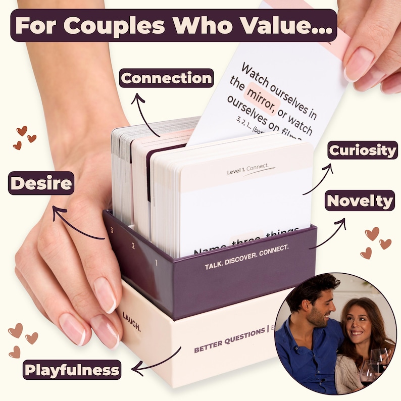 Close-up of a hand pulling a conversation card from the Our Guilty Pleasures box, showing neatly stacked cards inside a beige box with a dark purple insert. The image reads: "For Couples Who Value... Desire, Connection, Curiosity, Playfulness and Novelty".