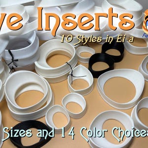 May include: A collection of white and black eye inserts in various shapes and sizes. The image displays 10 styles, 9 sizes, and 14 color choices. Some inserts have a tan interior. Text on the image reads "Eye Inserts".