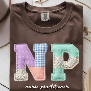 Puede incluir: Una camiseta marrón con las letras "NP" aplicadas en la parte delantera. Las letras están hechas de varias telas estampadas, incluyendo lunares, cuadros y estampados florales. Las palabras "nurse practitioner" están impresas debajo.