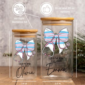 May include: Two glass jars with bamboo lids, each featuring a pink and blue striped bow with a stethoscope. The jars are labeled "L&D Nurse Est. 2025" with personalized names "Olivia" and "Emma". The jars are 5 inches tall and come in 10 oz and 20 oz options.