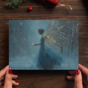 Pode incluir: Uma impressão artística retangular com uma ilustração digital de uma figura com asas translúcidas vestindo um vestido azul fluido. A figura está num ambiente de floresta escura e nevada, iluminada por partículas de luz dourada.