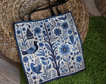 May include: A blue and white tote bag with a floral pattern and birds. The bag has black straps.