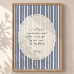 Può includere: Una stampa artistica incorniciata con uno sfondo a righe verticali blu e bianche. Al centro, un ovale color crema con un bordo smerlato simile al pizzo contiene il testo: Fear not, for I have redeemed you: I have called you by your name: You are Mine. Isaiah 43:1.