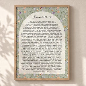 Peut inclure: Une affiche murale rectangulaire dans un cadre en bois clair, présentant un fond vert sauge avec un motif floral délicat. Au centre, un panneau crème en forme d'arche contient le texte complet de Proverbes 31:10-31 en police noire.