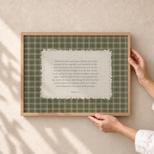 Op de afbeelding: Een rechthoekig ingelijst wandkunstwerk met een groen en wit ruitjespatroon op de achtergrond. In het midden bevindt zich een gebroken witte stof met gerafelde randen, bedrukt met de tekst van Psalm 1:1-3 in een donkergrijs schreeflettertype.