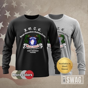 May include: Black long-sleeve shirt with a green snake and the text "J.O.T.C. Jungle Operations Training Center" and "Jungle Expert No Obstacle Too Difficult Fort Sherman Panama".  A gray long-sleeve shirt with the text "T.C. Training Center" is visible in the background.