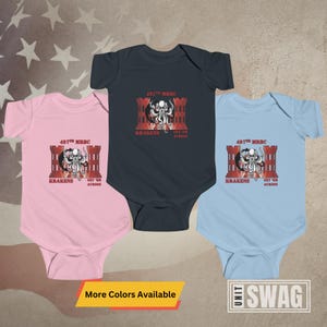 May include: Three baby onesies in pink, blue, and dark blue with a graphic print of a red brick building with a kraken monster inside. The text on the onesies reads "497th MRBC KRAKENS GET 'EM ACROSS".