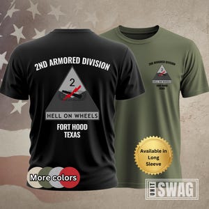 May include: A black short-sleeve t-shirt featuring the 2nd Armored Division Hell on Wheels logo with a red lightning bolt and tank graphic, and an olive green t-shirt with a smaller version of the same logo on the chest, both displaying Fort Hood Texas.