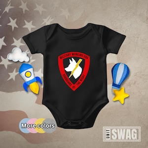 May include: Black baby bodysuit with a red, white, and yellow graphic. The graphic features a dog silhouette, lightning bolt, and the text "MILITARY WORKING DOG GUARDIANS OF THE NIGHT". Additional colors are shown below the bodysuit.