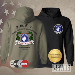 May include: Two hooded sweatshirts, one olive green and one black, featuring the text "J.O.T.C. Jungle Operations Training Center" and a graphic with snakes and a medical symbol. The olive green sweatshirt also has the text "More colors" below it.