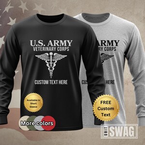 May include: Black long-sleeve t-shirt with white text that reads "U.S. ARMY VETERINARY CORPS" and a white caduceus symbol. The shirt also has the text "CUSTOM TEXT HERE" in white. A gray long-sleeve t-shirt with the same design is shown in the background. Both shirts have a gold seal with the text "FREE Custom Text".