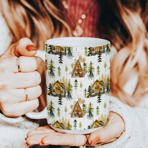 May include: White ceramic mug with a repeating pattern of watercolor illustrations of small green trees and brown cabins with white trim.