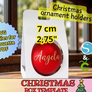 Puede incluir: Una caja blanca para adornos navideños con un adorno rojo en su interior. El adorno está personalizado con el nombre "Angela" en escritura dorada. La caja está etiquetada como "Christmas ornament holders!" y "Christmas box template". El adorno tiene 7 cm de diámetro.