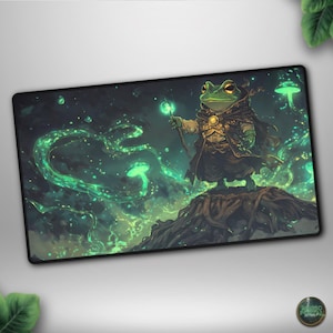 May include: A rectangular mousepad featuring a green frog wizard with a staff, standing on a tree root. The background is a dark, mystical scene with glowing green elements. The frog is wearing a dark cloak and gold armor.