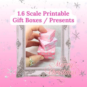 May include: Three small pink gift boxes with white snowflake and star patterns are stacked. The boxes are held in a hand, and the image has text that reads "1.6 Scale Printable Gift Boxes / Presents" and "Merry Christmas."