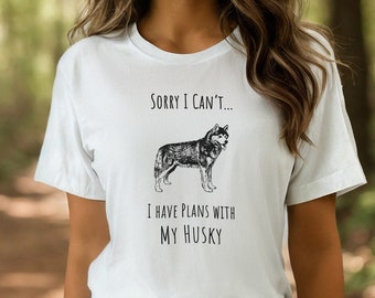 May include: White t-shirt with a black and white illustration of a husky dog. The text on the shirt reads "Sorry I can't... I have plans with my husky."