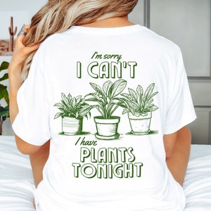 May include: White t-shirt with green text that reads "I'm sorry I can't I have plants tonight". The text is surrounded by three drawings of potted plants.