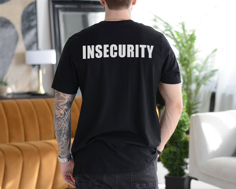 May include: A black t-shirt with the word "INSECURITY" printed in white on the back.