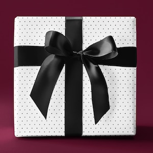 May include: A white gift box with black polka dots and a black satin ribbon tied in a bow.