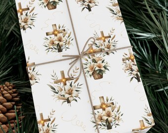 May include: White gift wrap with a repeating pattern of brown crosses and white lilies. The crosses have gold accents and the lilies are surrounded by green leaves. The gift wrap is tied with a brown twine bow.
