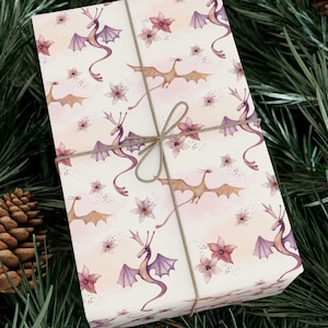 May include: A white gift wrap with a repeating pattern of pink and purple dragons and pink flowers. The gift wrap is tied with a brown twine bow.