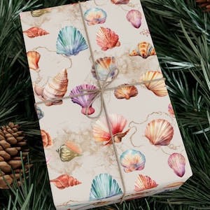 May include: A gift wrapped in white wrapping paper with a seashell pattern. The paper has a marbleized effect and features watercolor seashells in shades of pink, blue, orange, and purple.