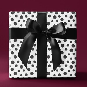 May include: A white gift box with a black polka dot pattern and a black satin ribbon tied in a bow.