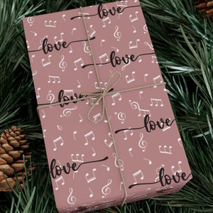 May include: Pink gift wrap with a repeating pattern of white musical notes and the word "love" written in black cursive.