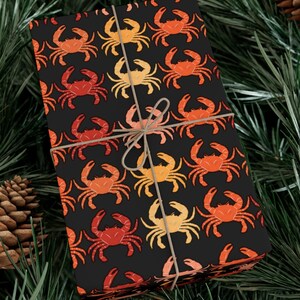 May include: A black gift wrap with a repeating pattern of orange, red, and yellow crabs. The wrap is tied with a brown twine bow.