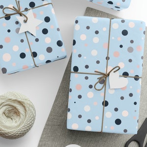 May include: Two gift boxes wrapped in blue paper with a white polka dot pattern. The boxes are tied with twine and have a white star and heart tag attached.