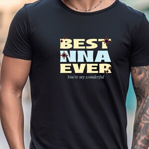 May include: Black t-shirt with the text "BEST NNA EVER" in a stylized font. The text is in a combination of beige and light blue colors, with decorative starburst accents. The phrase "You're my wonderful" is printed below the main text.