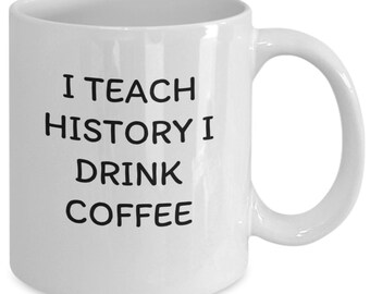 May include: White ceramic coffee mug with black text that reads "I teach history I drink coffee".